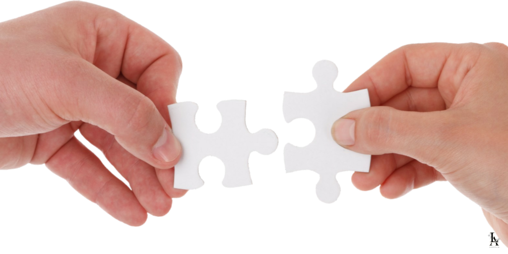 Two hands holding white puzzle pieces, about to fit them together.