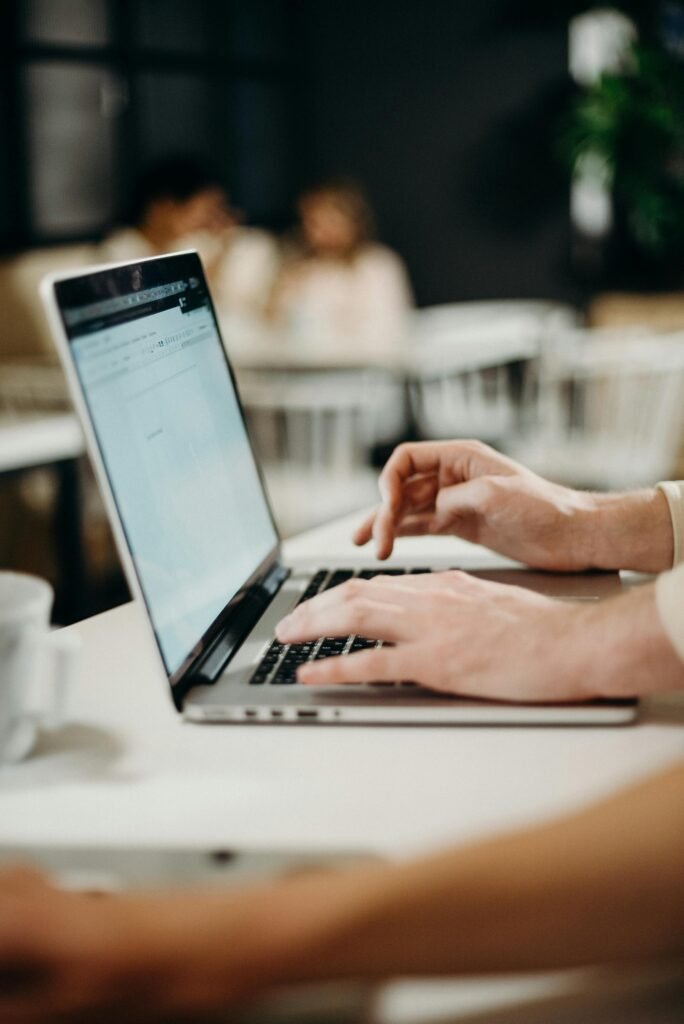 Close-up of hands typing on a laptop in a collaborative workspace.